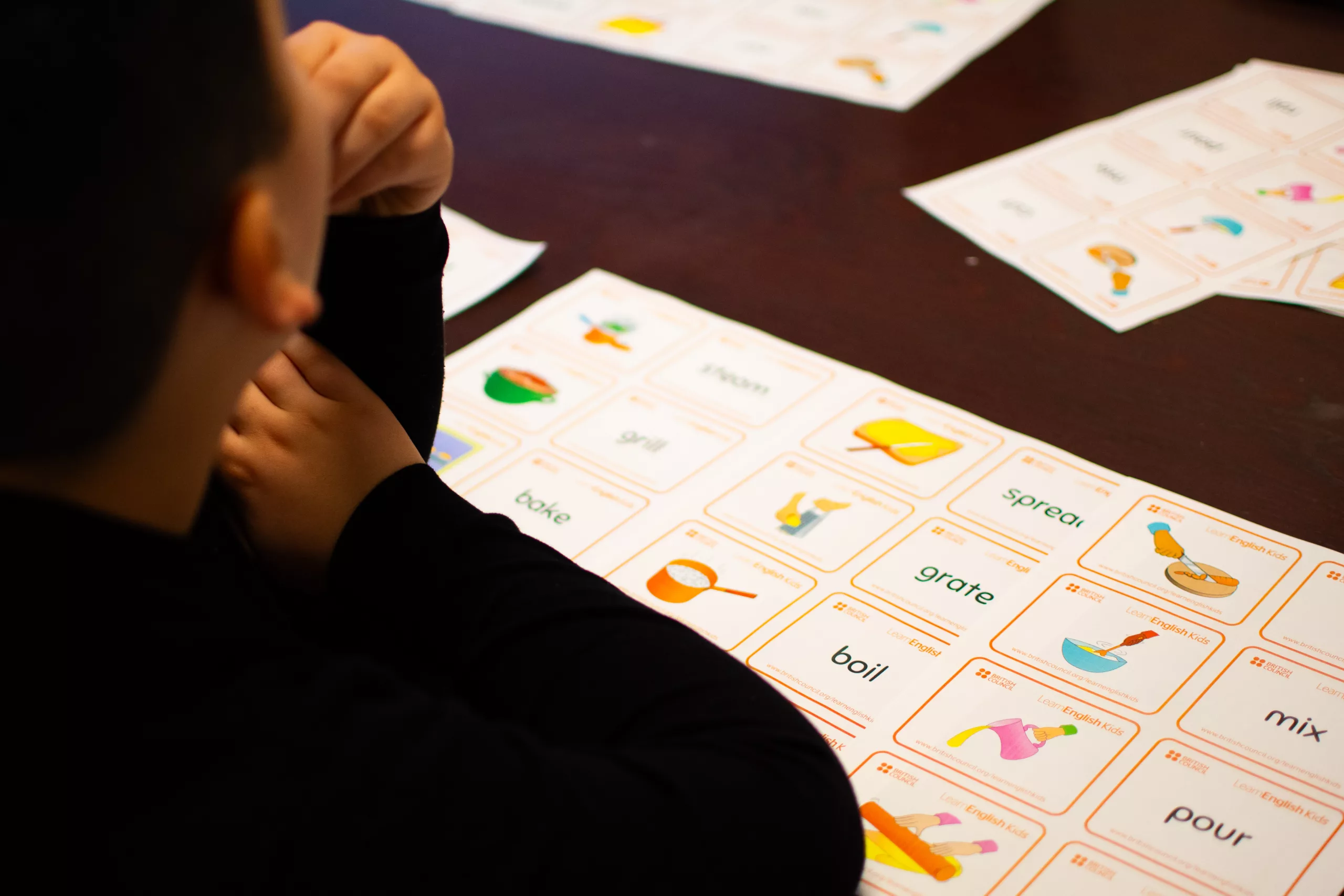 Enfant découvrant les bases de l’anglais à l’aide de cartes illustrées lors d’une activité ludique