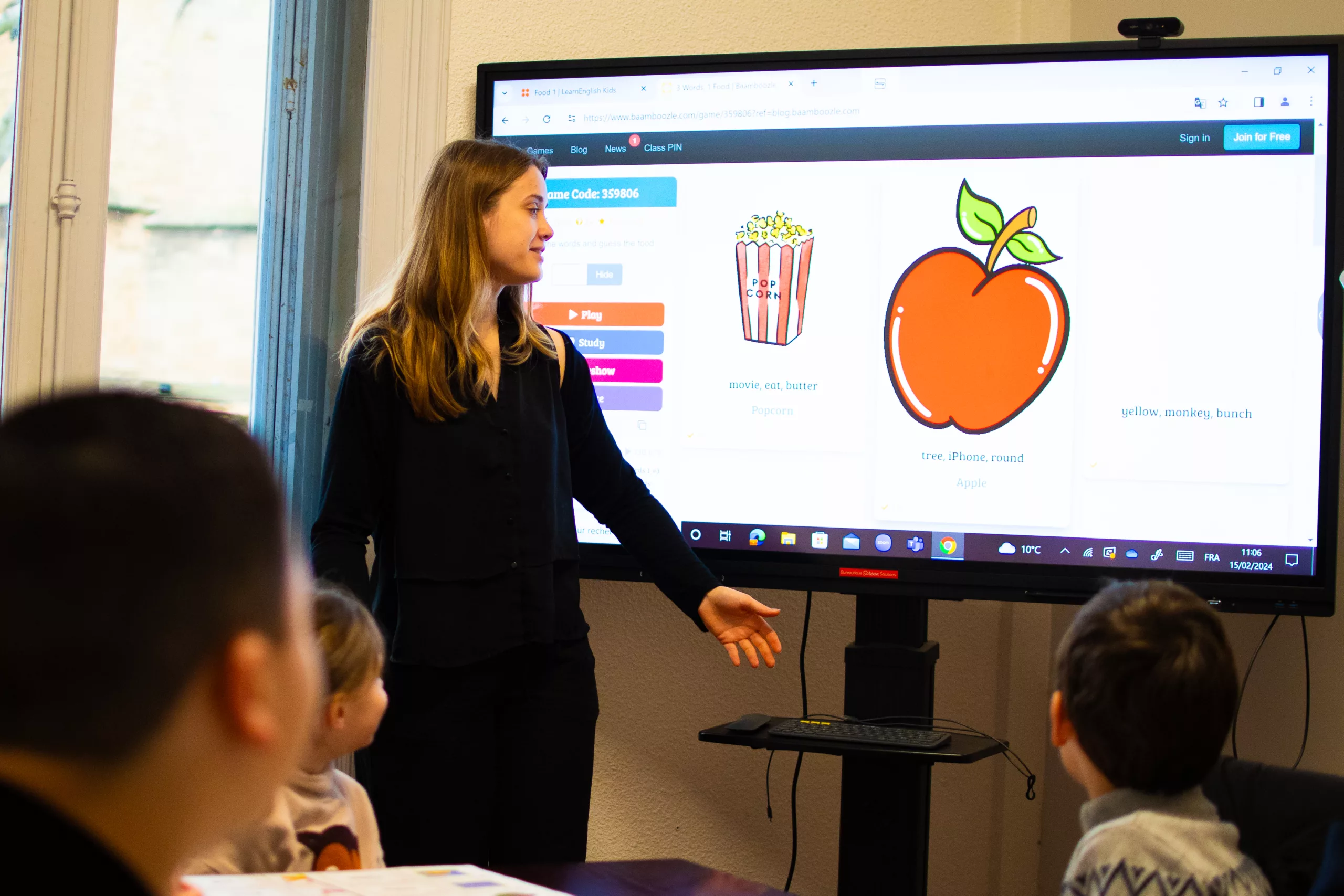 Animatrice accompagnant des enfants lors d’un atelier d’éveil à l’anglais avec support interactif