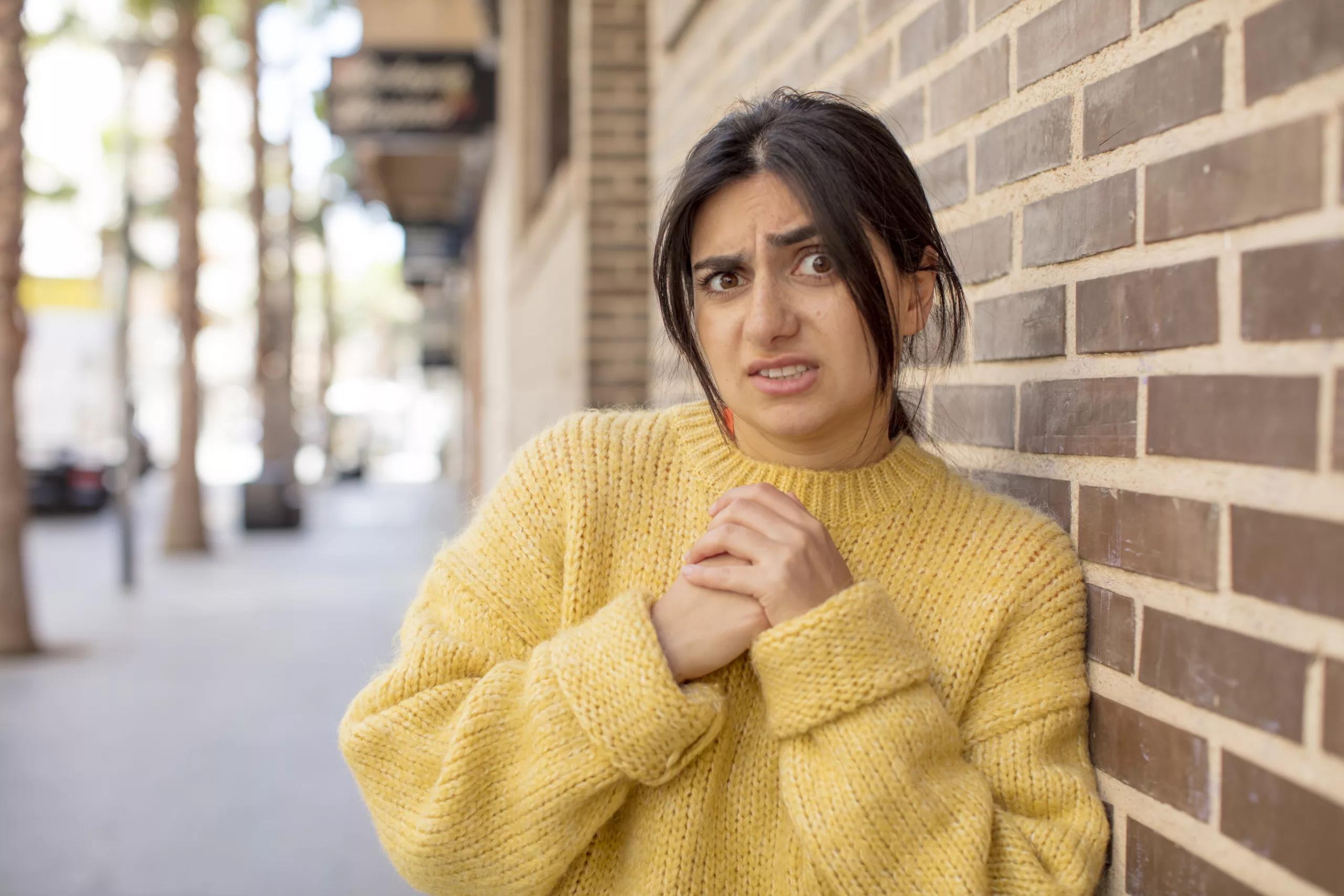 Jeune femme avec l'air inquiète appuyée contre un mur