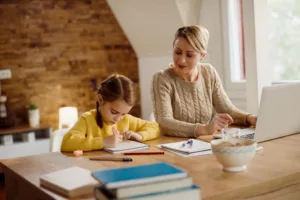 Une petite fille suit un cours à domicile dans un cadre chaleureux avec une professeure d'anglais en présentiel