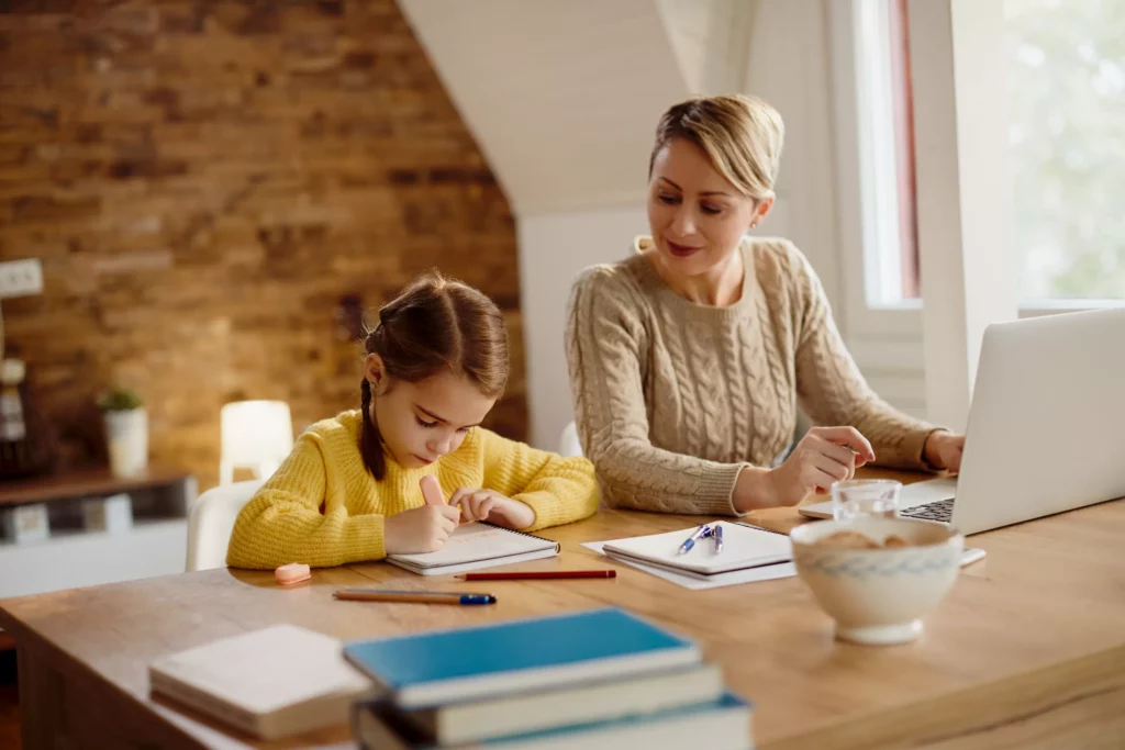 Une petite fille suit un cours d'anglais à domicile dans un cadre chaleureux avec une professeure d'anglais en présentiel